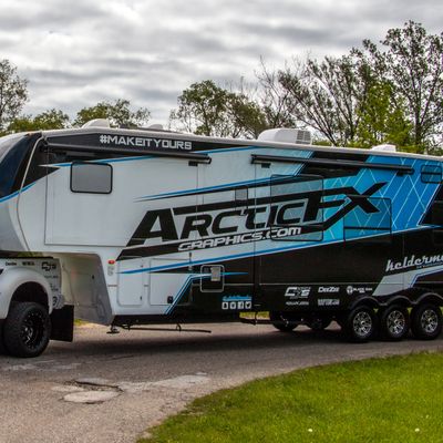 A commercial trailer with a custom vinyl wrap with white, black and blue shapes, logos, and stripes.