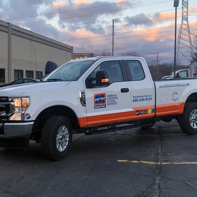 A commercial work truck with a custom vinyl wrap with orange, white, and blue logos and text