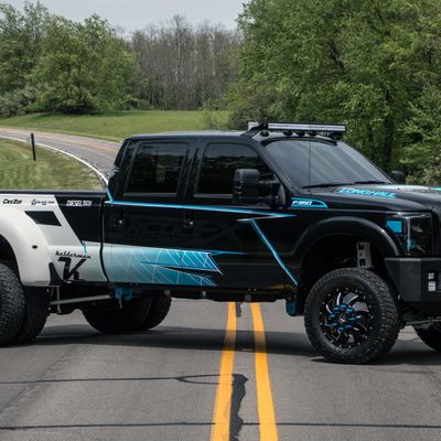 A commercial ford truck with a custom vinyl wrap with white, black and blue shapes, logos, and stripes