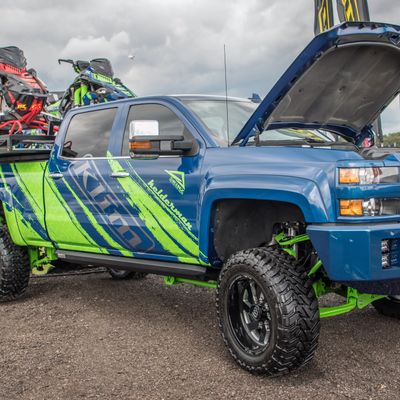 A commercial work truck with a custom vinyl wrap with lime green, gray, and blue logos and text with a simple grunge design