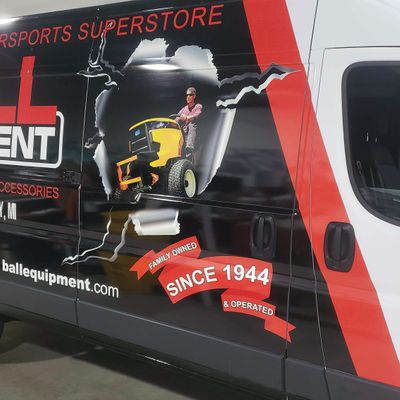 A commercial work van with a custom vinyl wrap for Ball Equipment colored red white and black