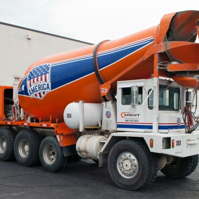 A commercial cement truck with a custom vinyl wrap of made in America design colored red, white, and blue stripes and flag on the barrel