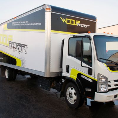 A commercial box truck with a custom vinyl wrap with lime green, black, and white logos and stripes