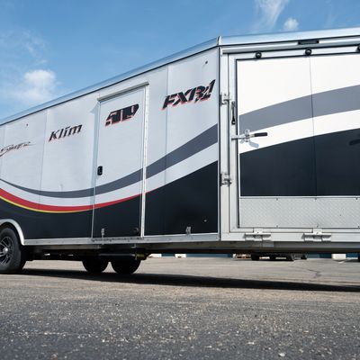 A snowmobile trailer with a custom vinyl wrap with yellow, white, gray and black lines and swirls.