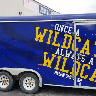A commercial trailer with a custom vinyl wrap with yellow, blue, and white logos and school design.