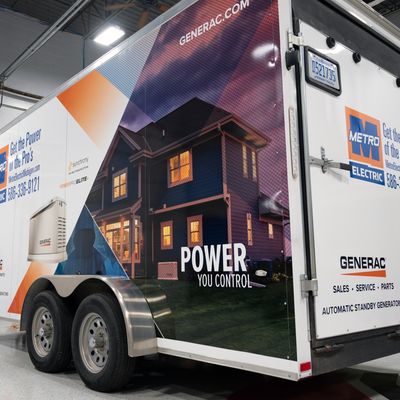 A commercial box trailer with a custom vinyl wrap with orange, black, and white logos and design with a photograph.