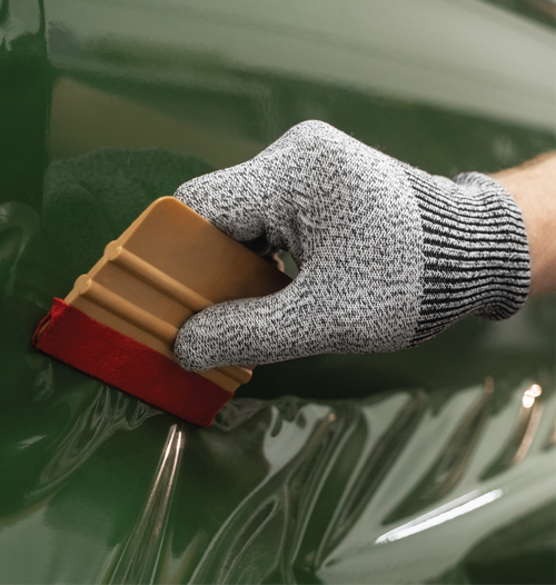 Closeup of a color change vinyl wrap being professionally applied to a vehicle