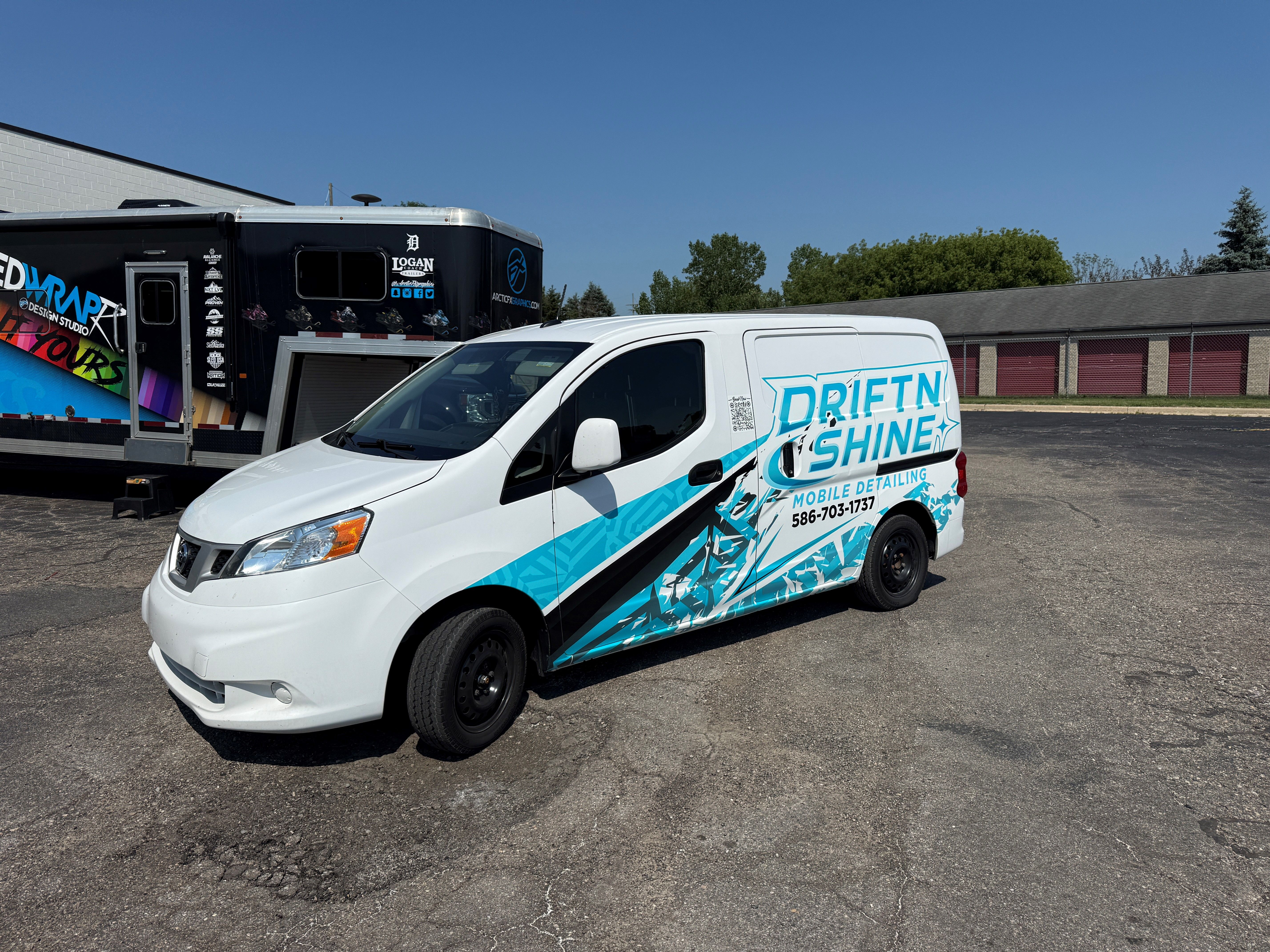 A commercial work vehicle with a custom vinyl wrap with blue and black text and logos.
