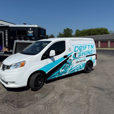 A commercial work vehicle with a custom vinyl wrap with blue and black text and logos.