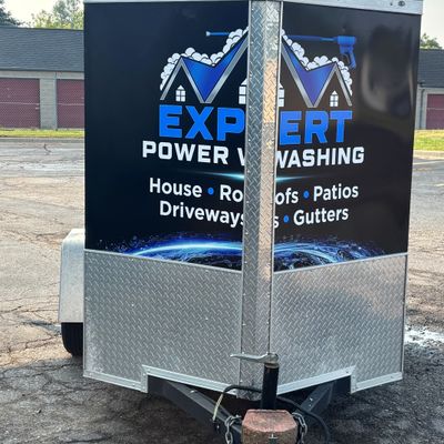 A commercial trailer with a custom vinyl wrap with blue and white text and logo