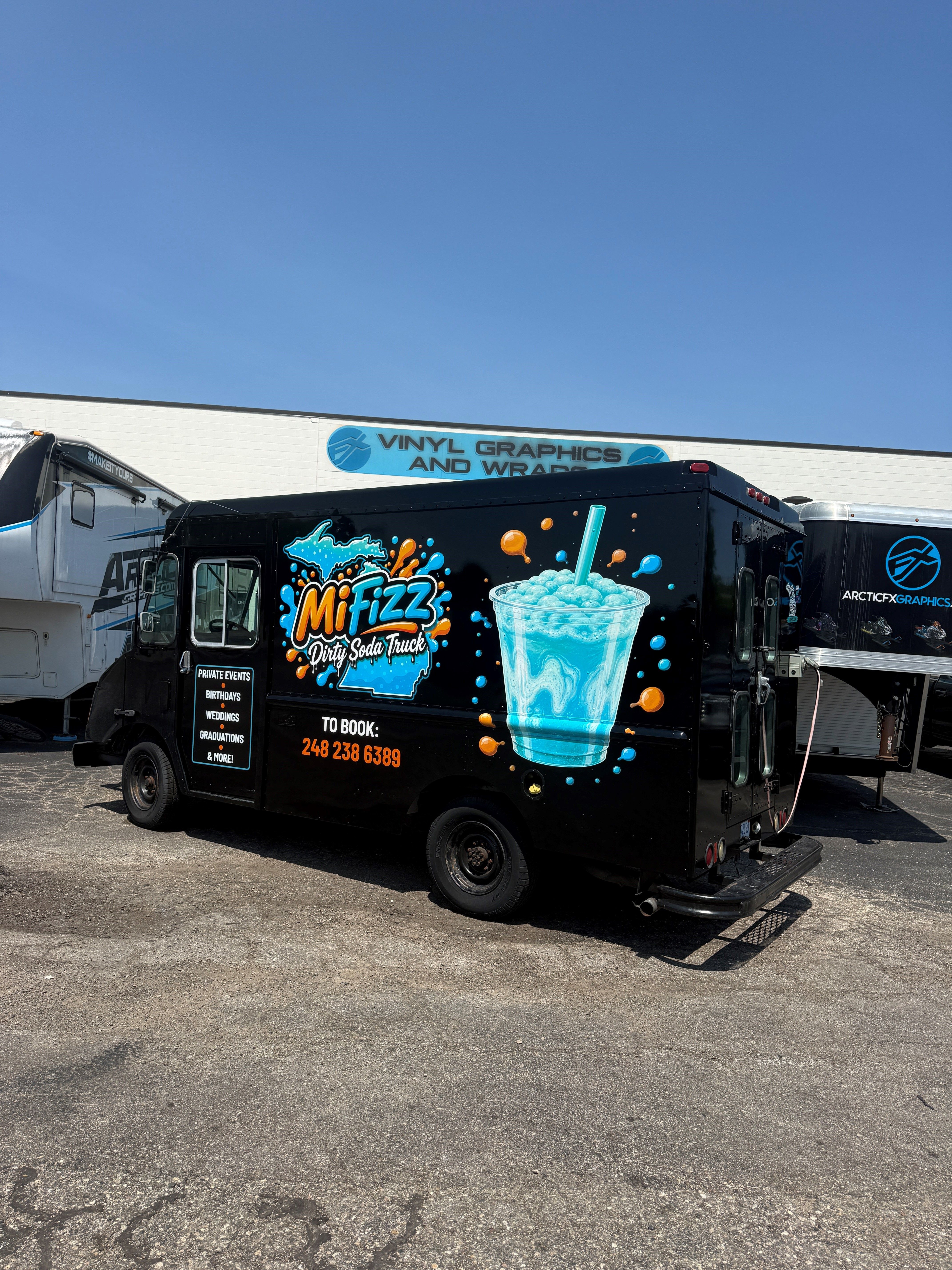 A commercial food truck with a custom vinyl wrap with text and logos.