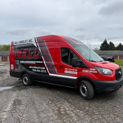 A commercial work van with a custom vinyl wrap with red, black, and grey logos and design