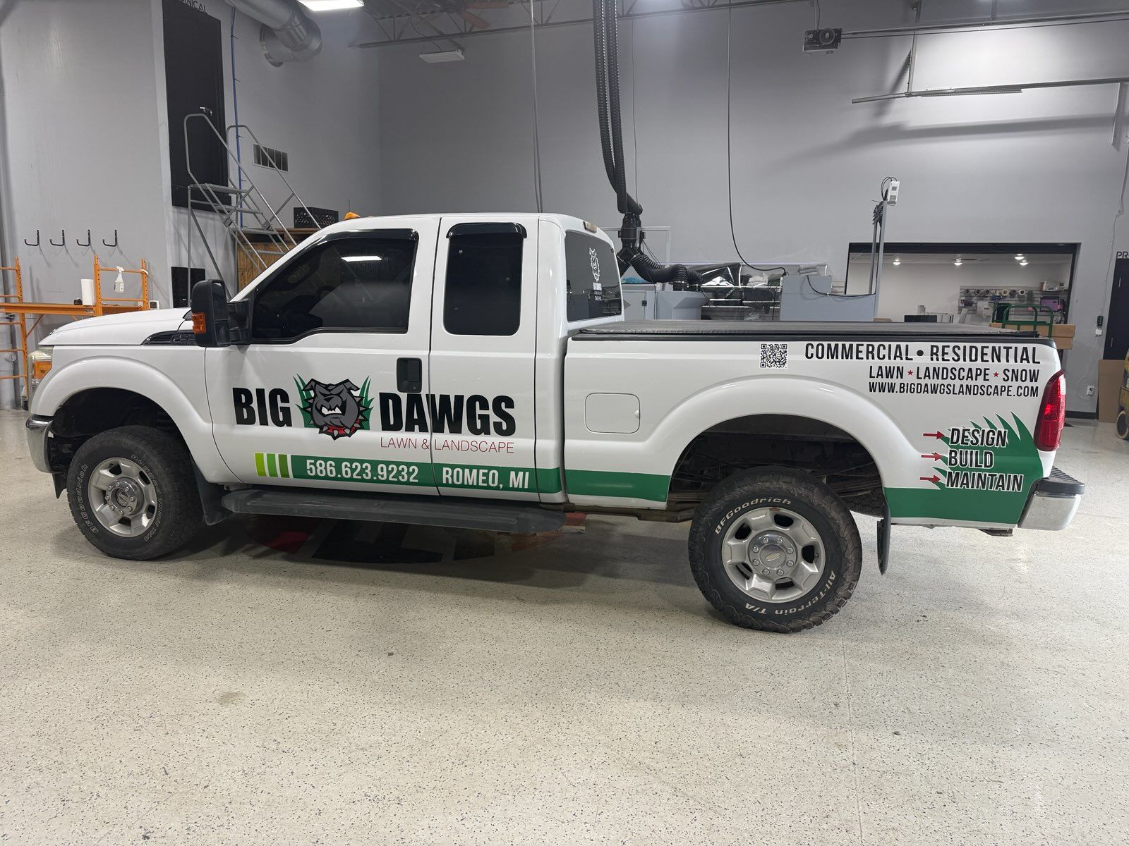 A commercial work truck with a custom vinyl wrap with black and green text and logo.