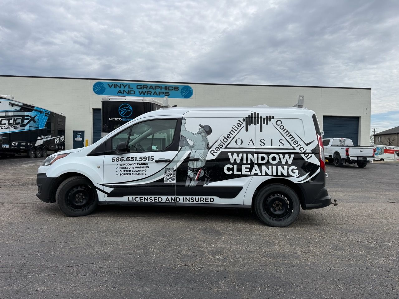 A commercial work van with a custom vinyl wrap with black text and design.
