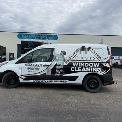A commercial work van with a custom vinyl wrap with black text and design.
