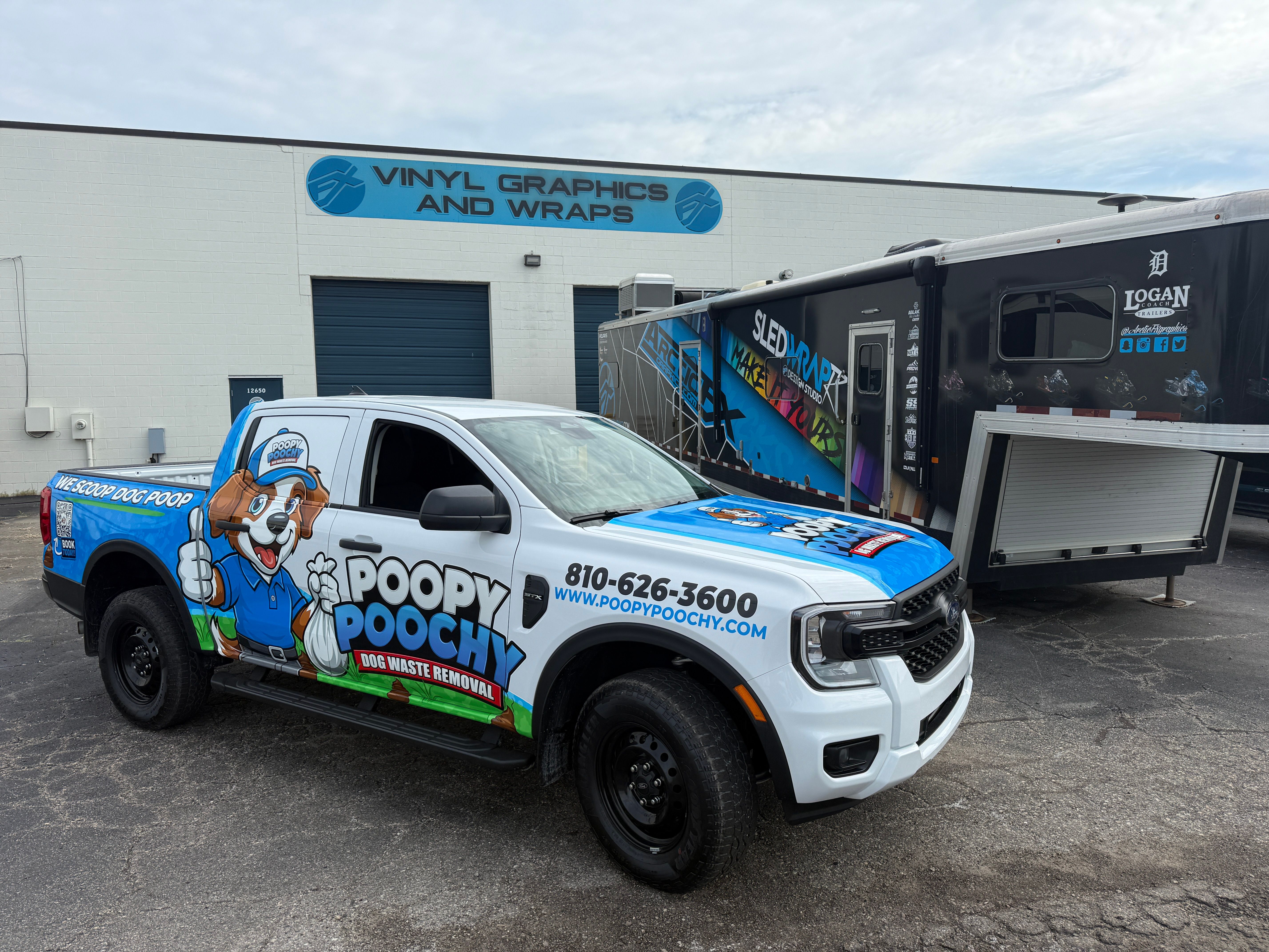 A commercial work truck with a custom vinyl wrap with blue and white text and dog logo.