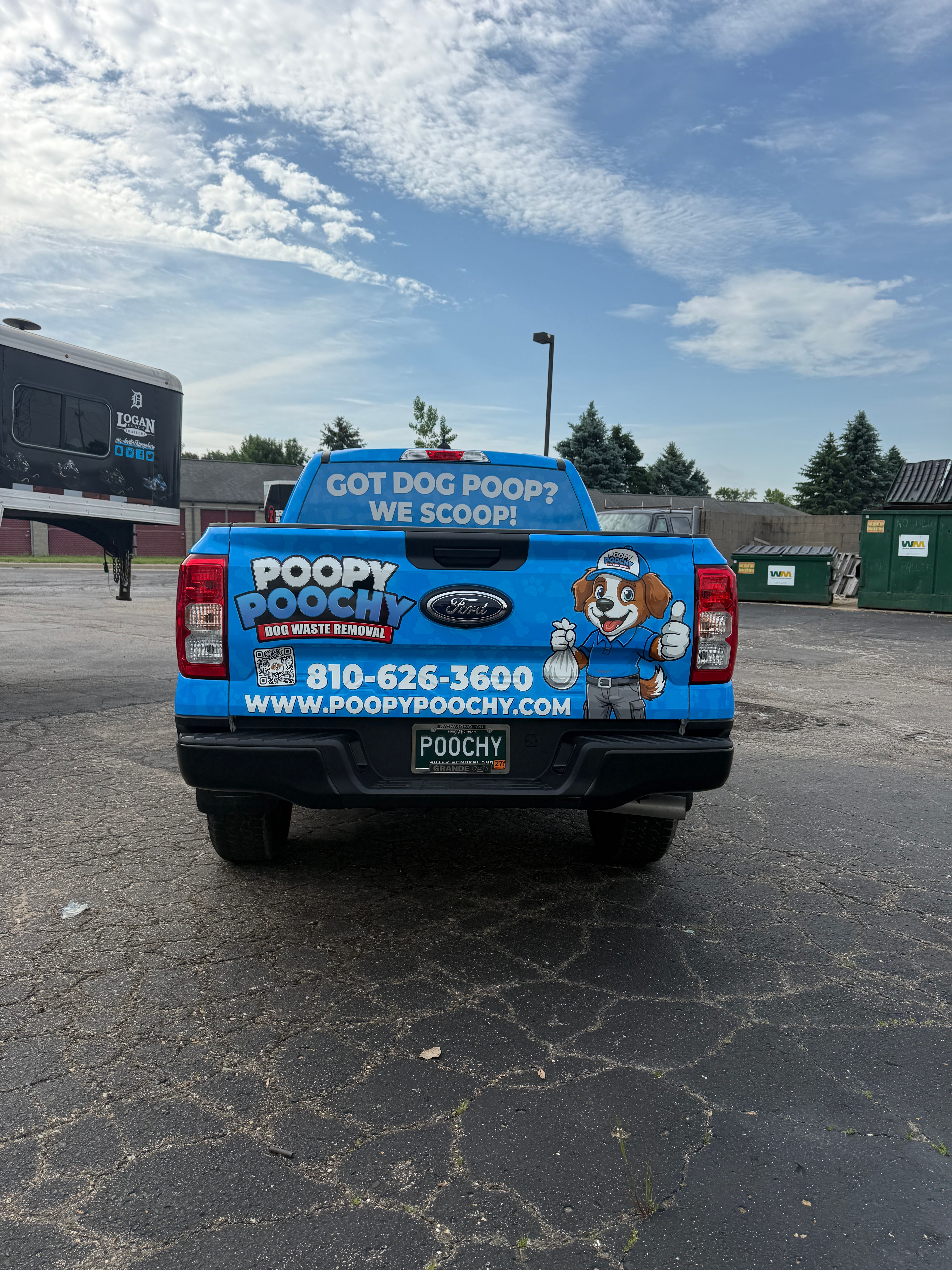 A commercial work truck with a custom vinyl wrap with blue and white text and dog logo.
