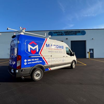 A commercial van with a custom vinyl wrap white, blue and red text and logo