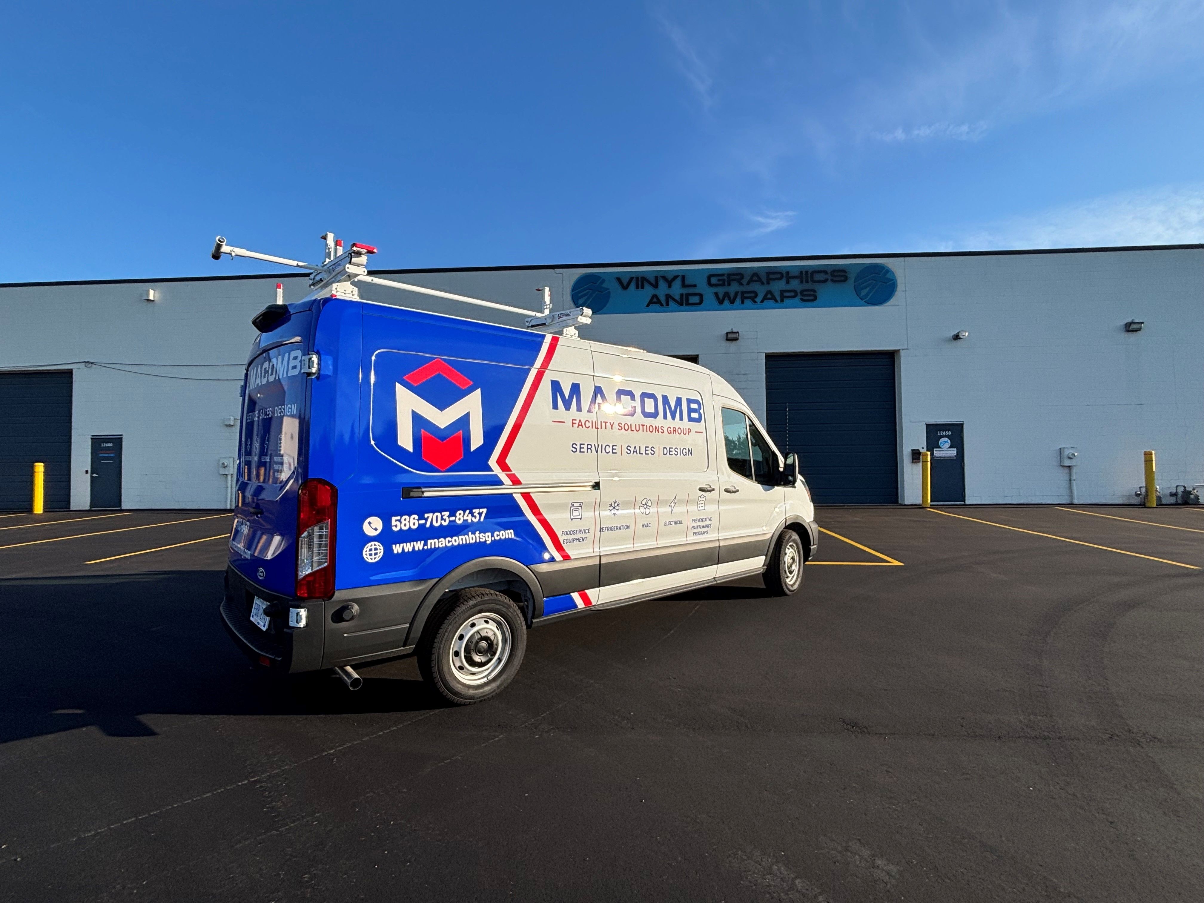A commercial van with a custom vinyl wrap white, blue and red text and logo