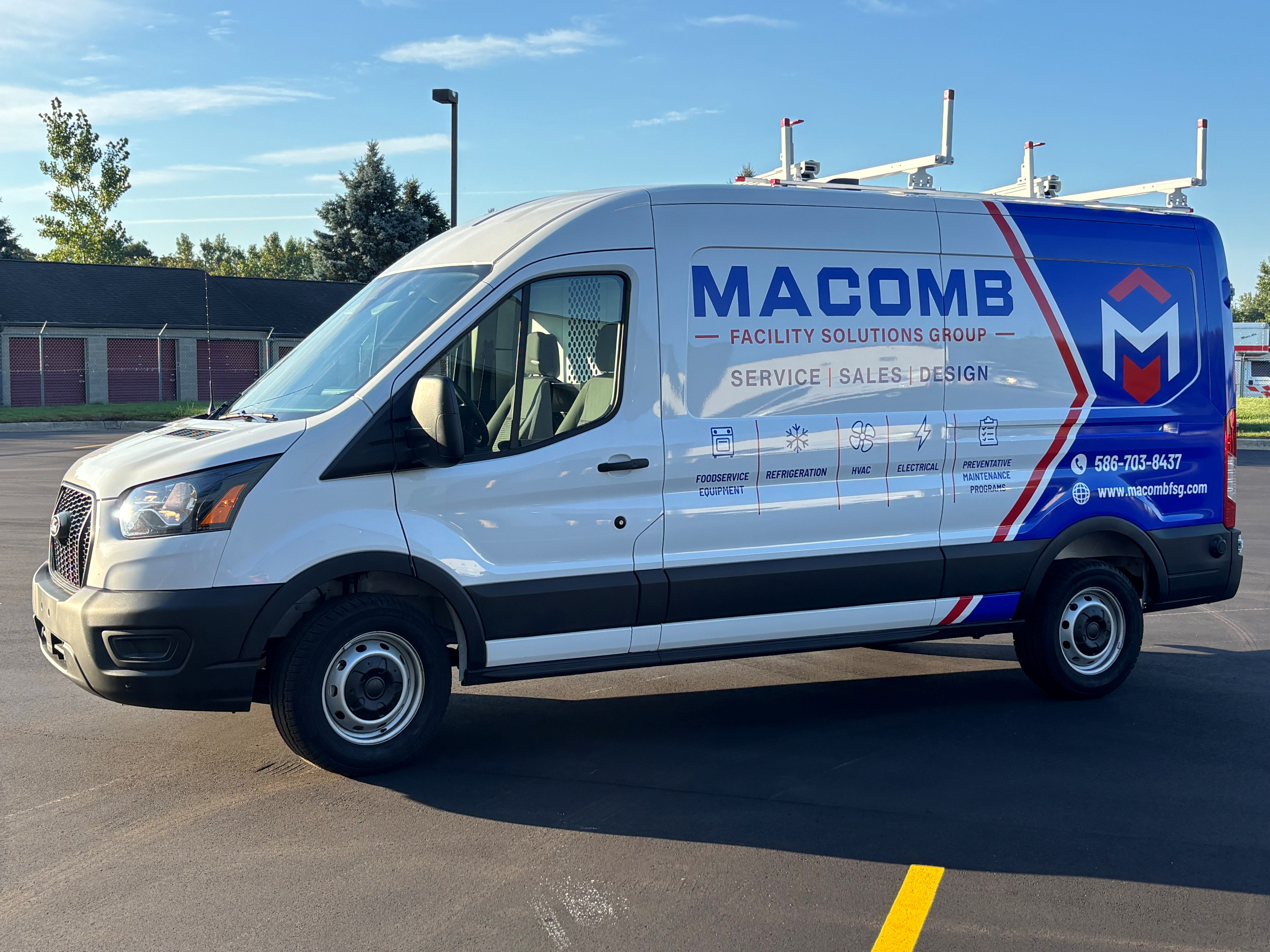 A commercial work van with a custom vinyl wrap with blue, white, and red text and logos