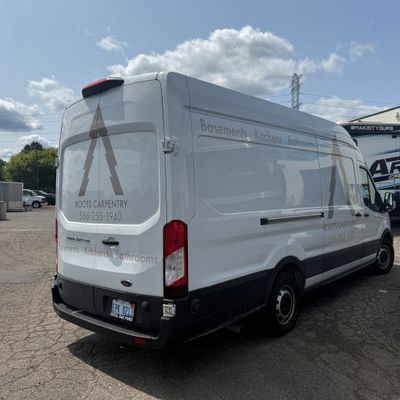 A commercial work van with a custom vinyl wrap with tan text and logo.