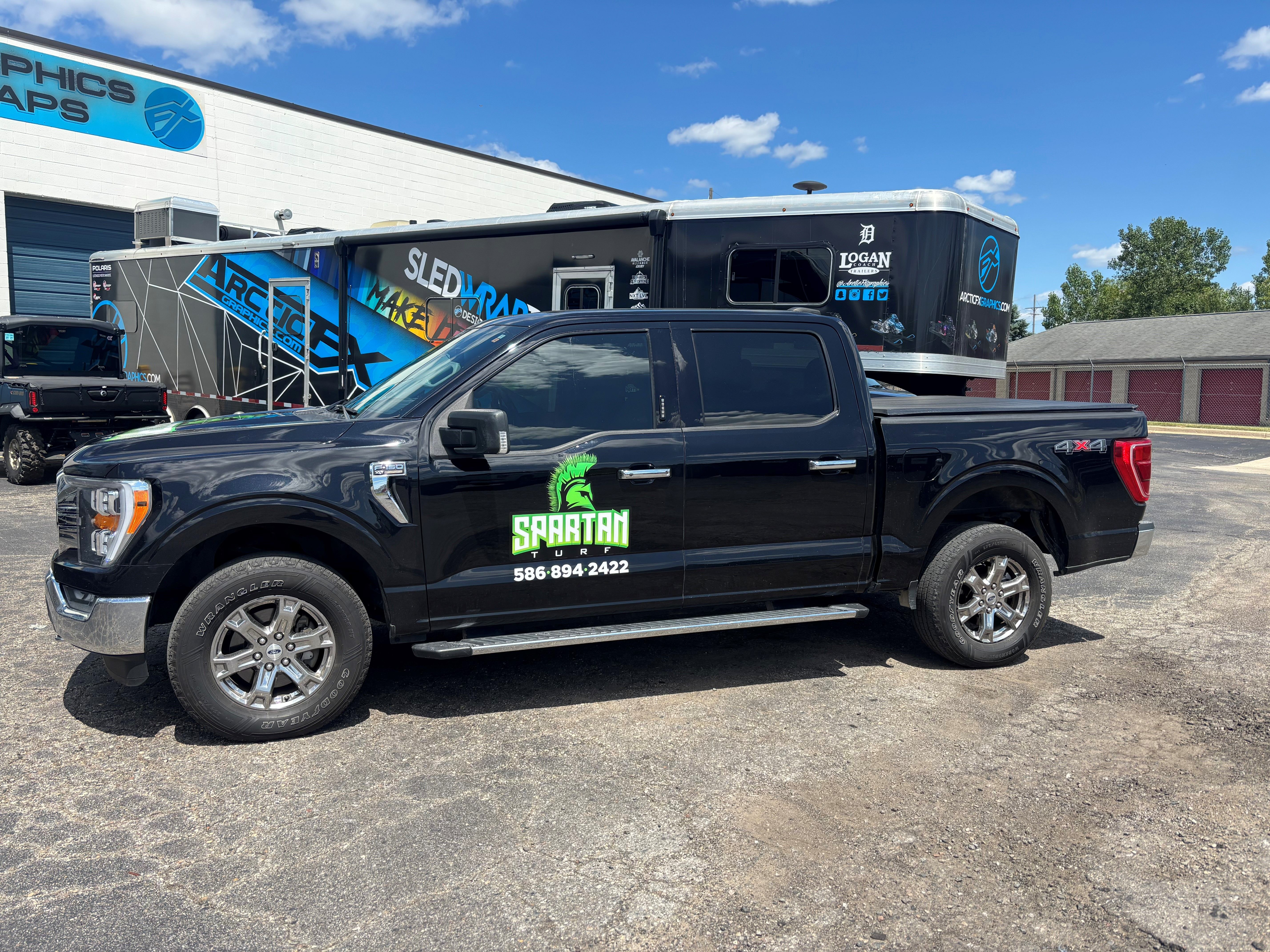 A commercial work truck with a custom vinyl wrap with green and white text and logo.