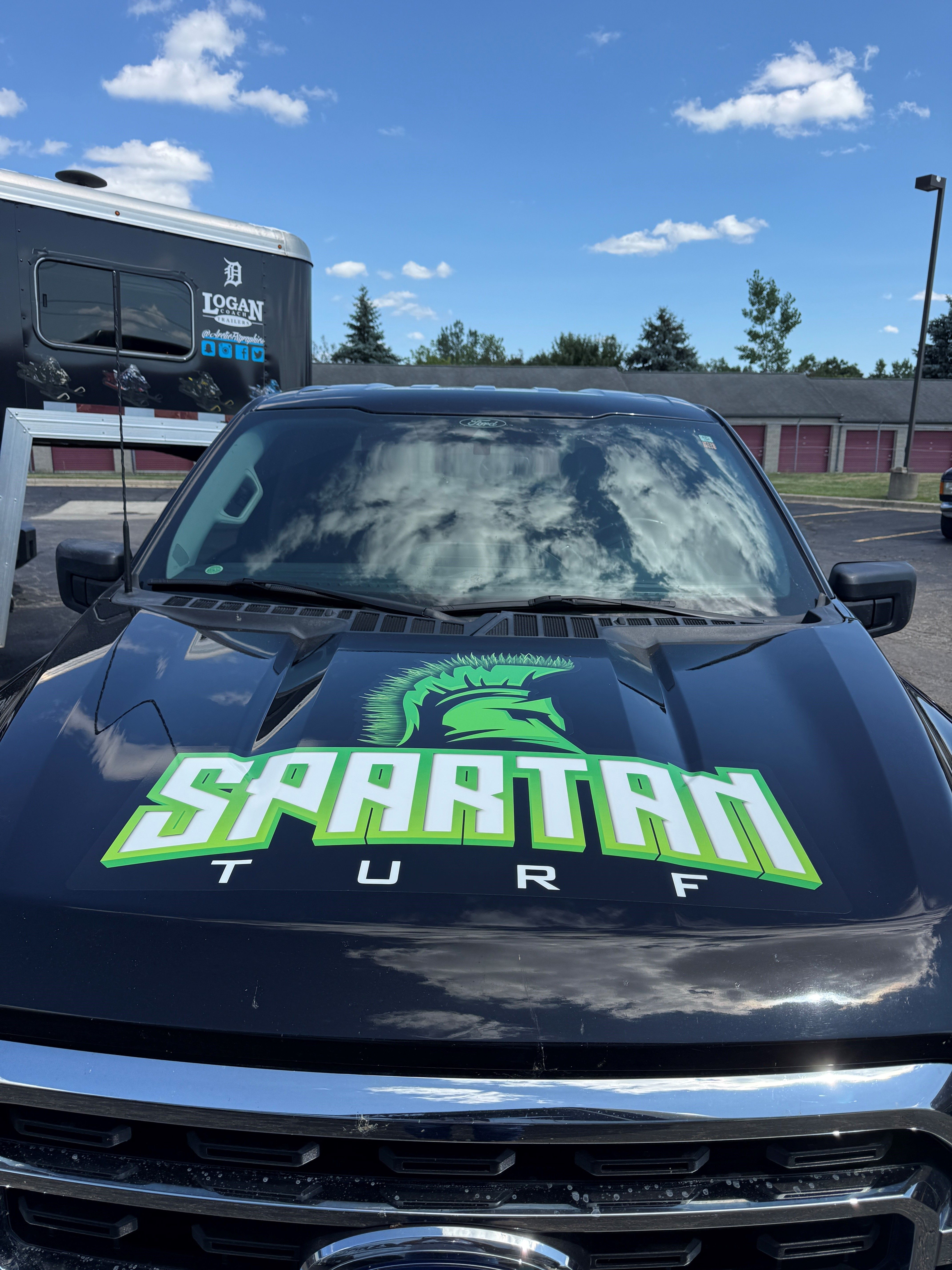 A commercial work truck with a custom vinyl wrap with green and white text and logo.