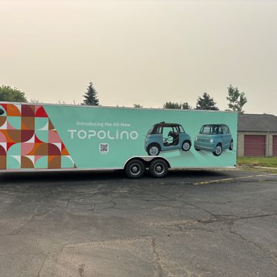 A commercial trailer with a custom vinyl wrap with white text and geometric design