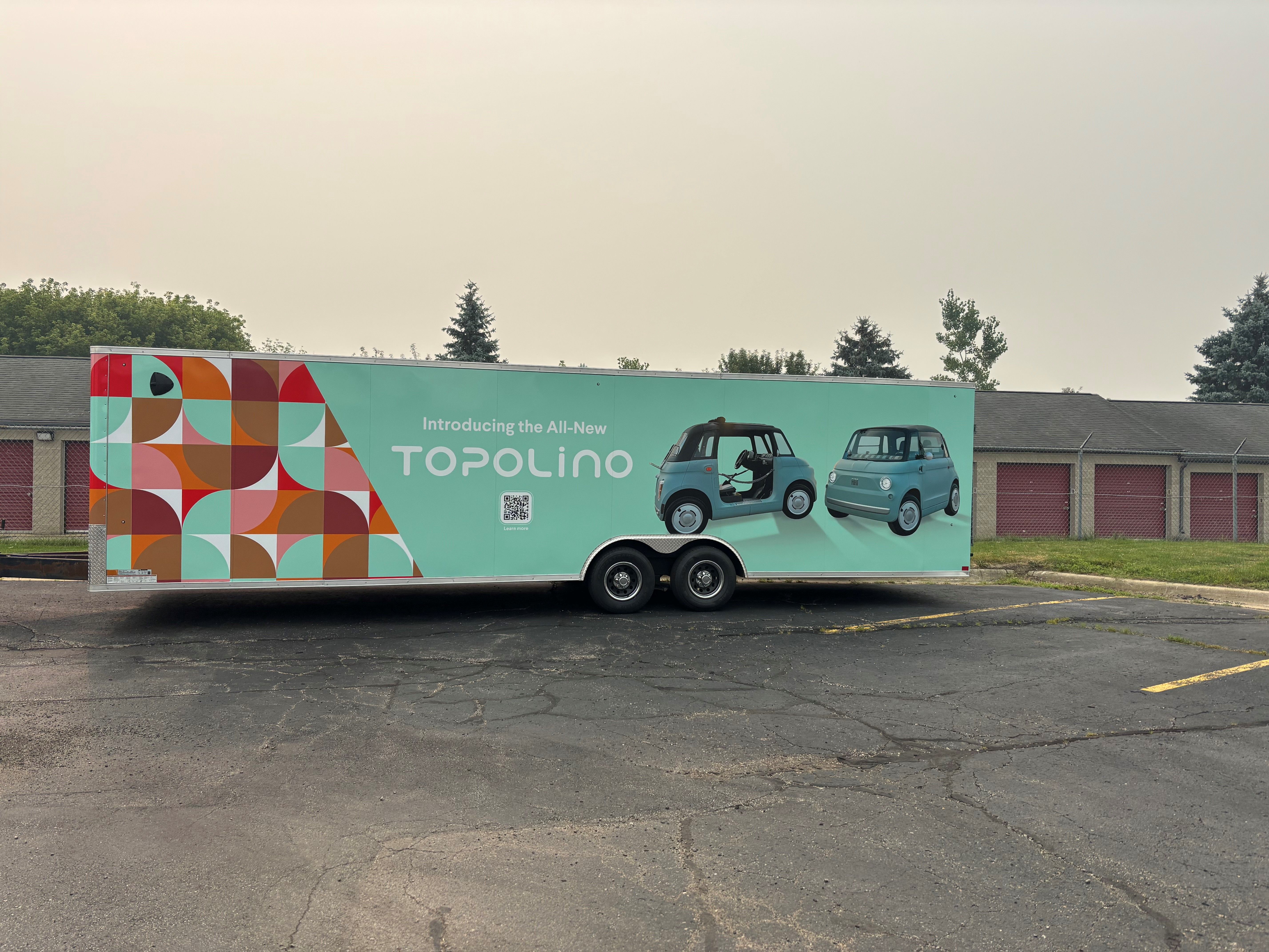 A commercial trailer with a custom vinyl wrap with white text and geometric design
