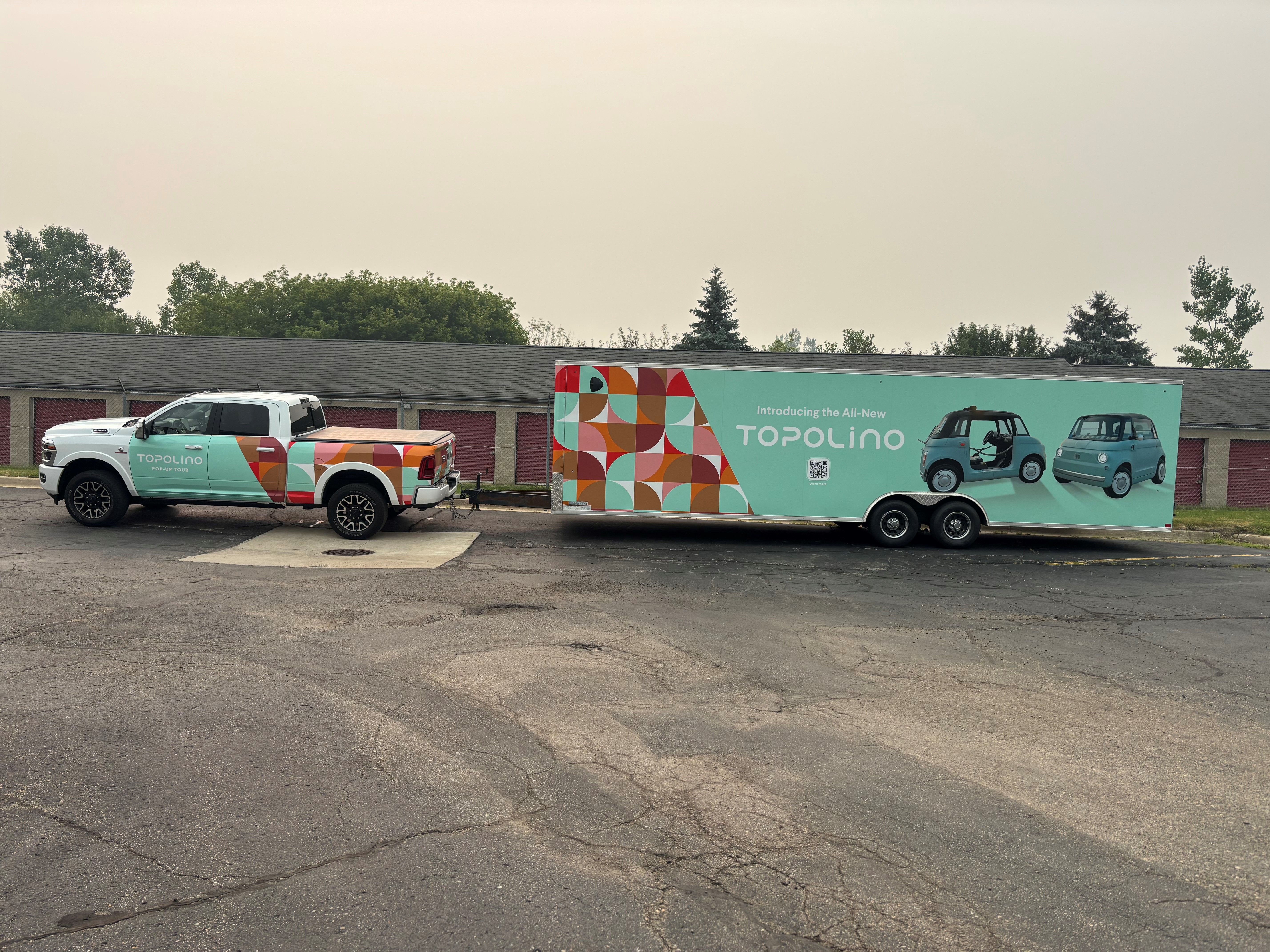 A commercial trailer with a custom vinyl wrap with white text and geometric design