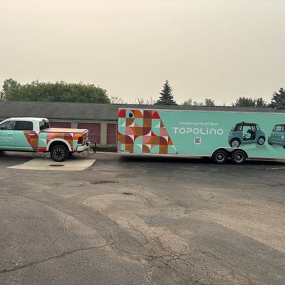 A commercial trailer with a custom vinyl wrap with white text and geometric design