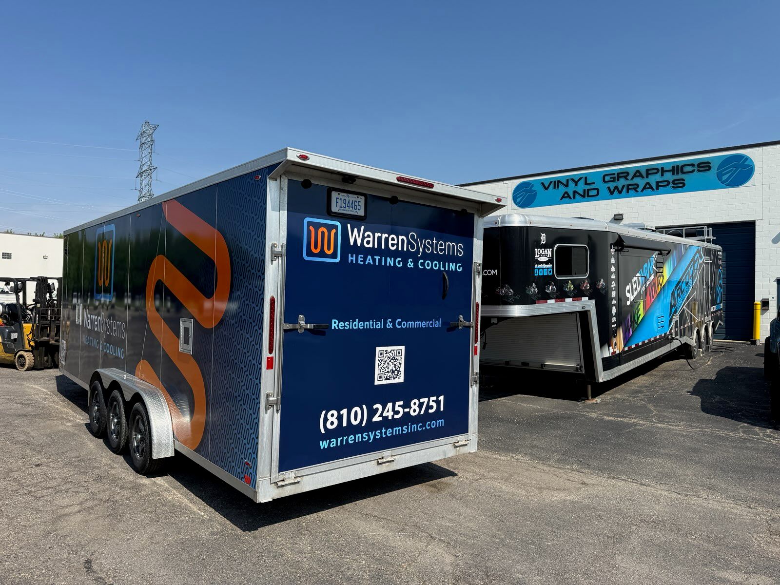 A commercial trailer with a custom vinyl wrap with white, blue, and orange logos.