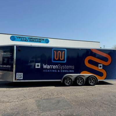 A commercial trailer with a custom vinyl wrap with blue, white, and orange logos.