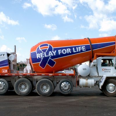 A commercial cement truck with a custom vinyl wrap of relay for life design colored purple and white ribbon and stripes on the barrel
