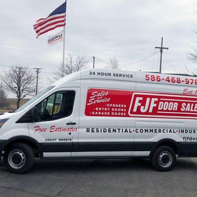 A commercial work van with a custom vinyl wrap with white, blue, and red logos and text