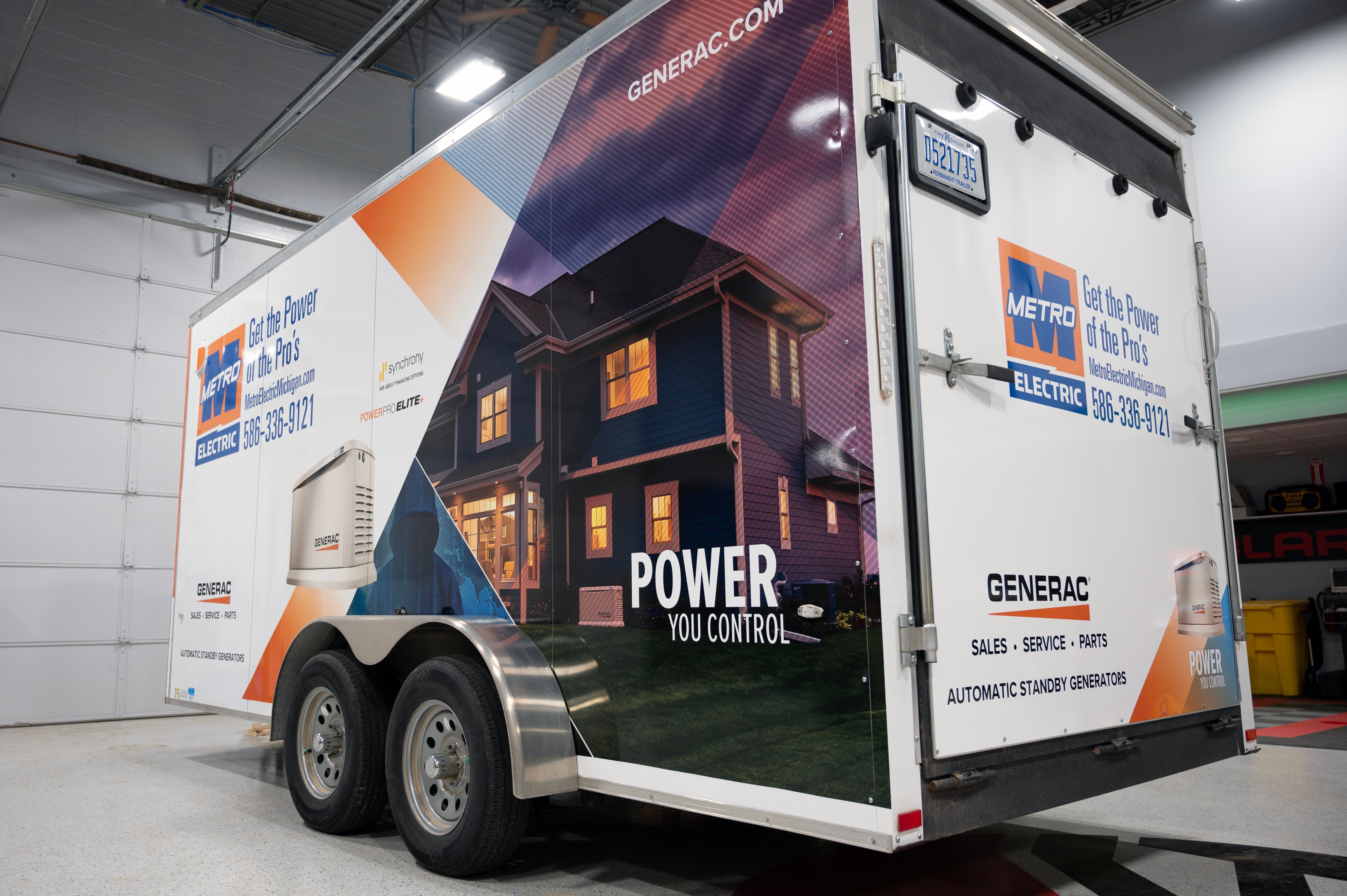 A commercial box trailer with a custom vinyl wrap with orange, black, and white logos and design with a photograph.