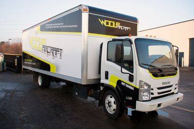 A commercial box truck with a custom vinyl wrap with lime green, black, and white logos and stripes
