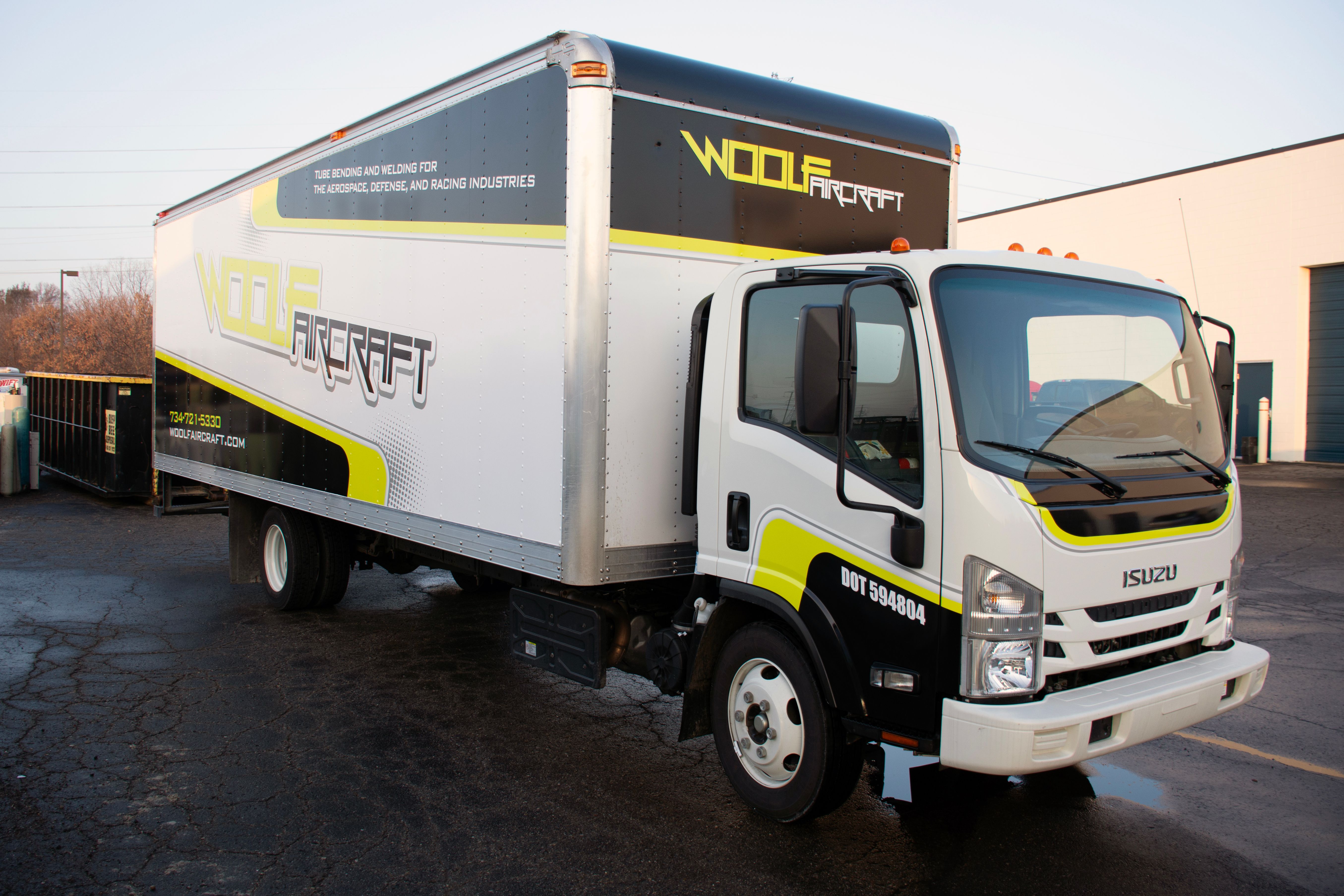 A commercial box truck with a custom vinyl wrap with lime green, black, and white logos and stripes