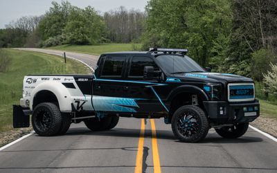 A commercial ford truck with a custom vinyl wrap with white, black and blue shapes, logos, and stripes