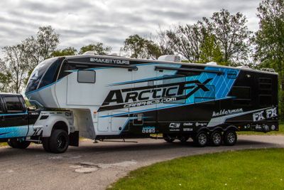 A commercial trailer with a custom vinyl wrap with white, black and blue shapes, logos, and stripes.