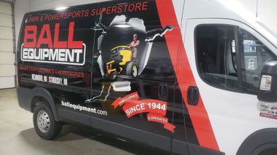 A commercial work van with a custom vinyl wrap for Ball Equipment colored red white and black