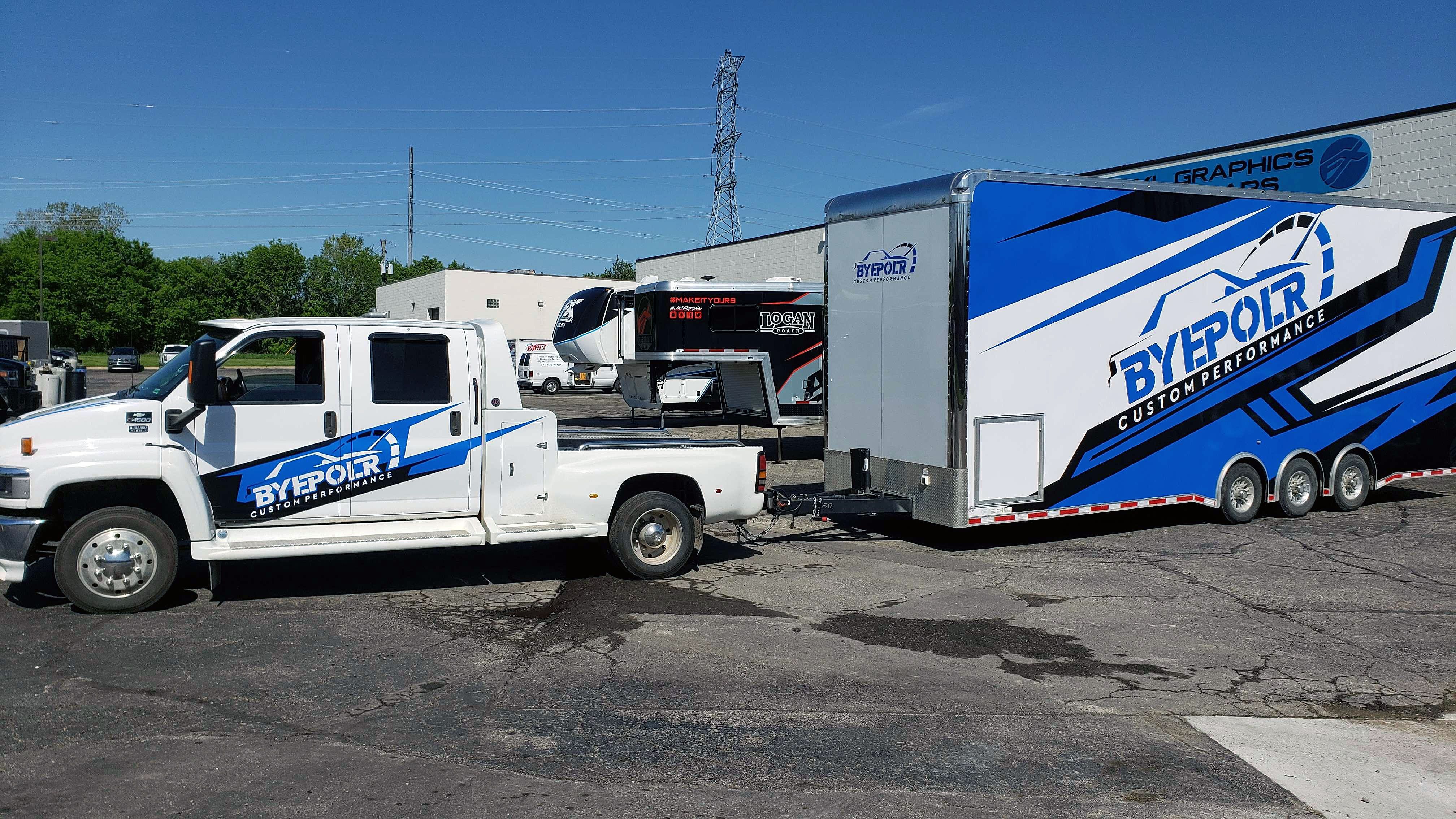 A commercial work truck and trailer with a custom vinyl wrap with white, black and blue shapes, logos, and stripes.
