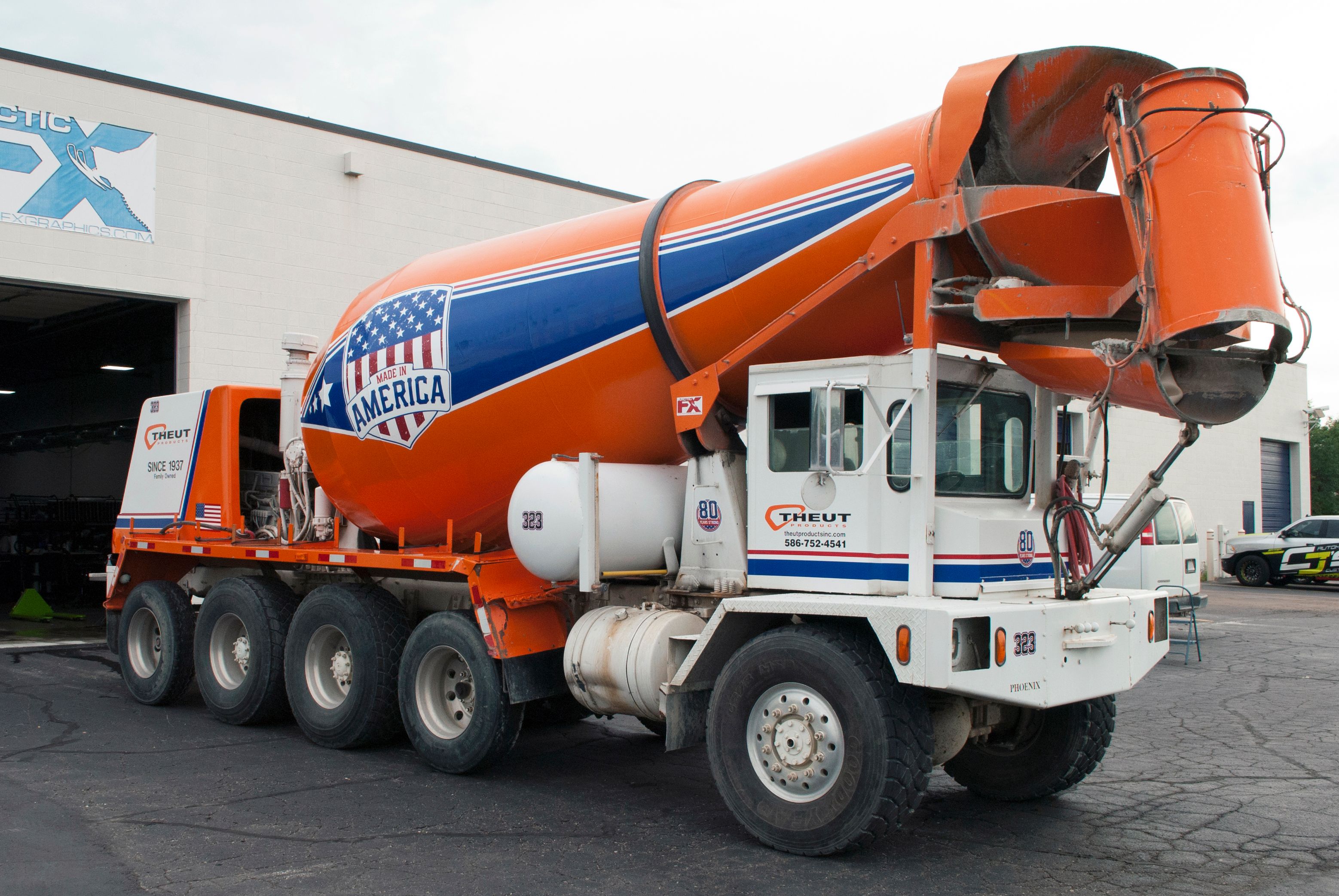 A commercial cement truck with a custom vinyl wrap of made in America design colored red, white, and blue stripes and flag on the barrel
