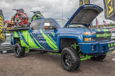 A commercial work truck with a custom vinyl wrap with lime green, gray, and blue logos and text with a simple grunge design