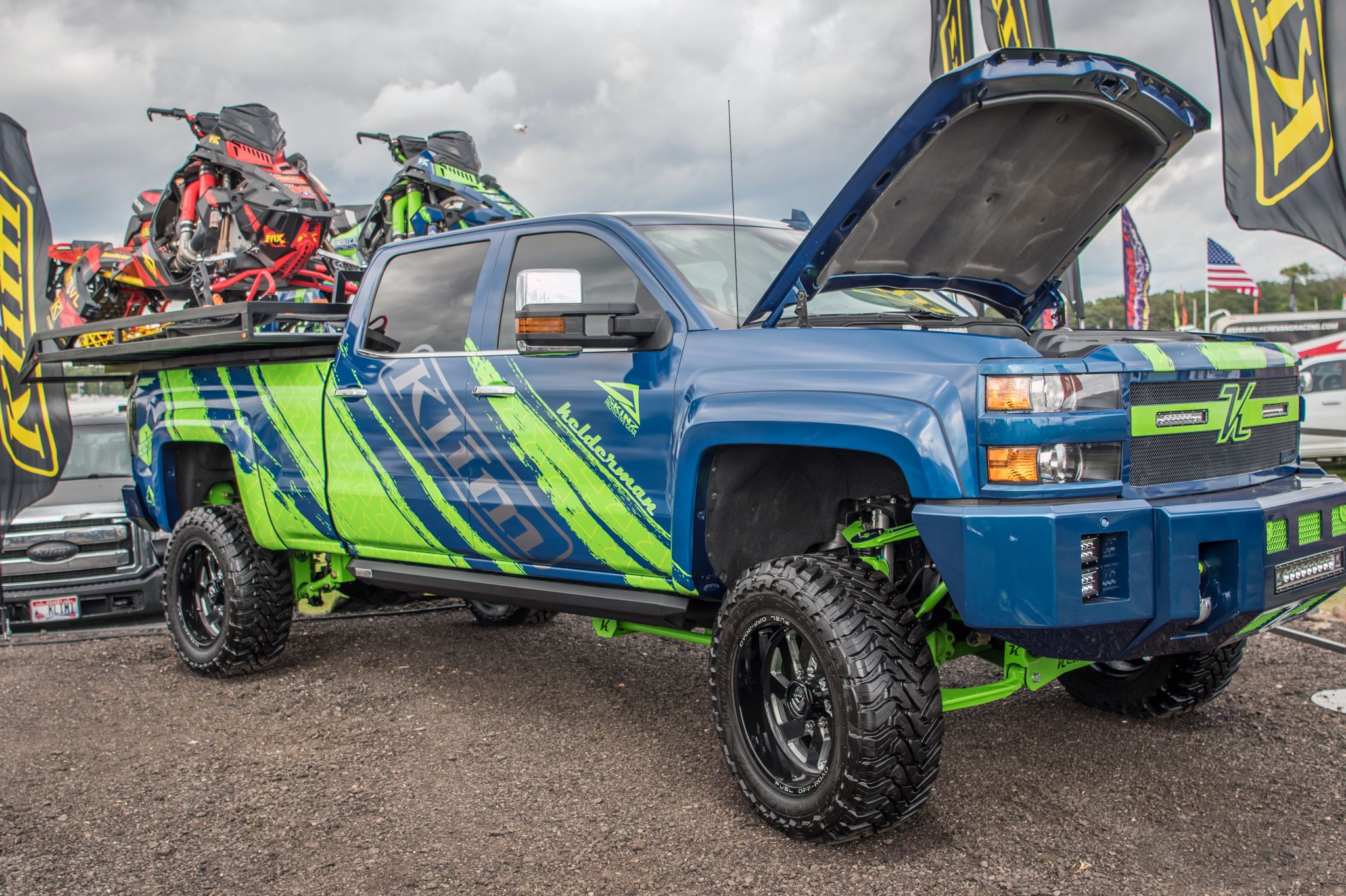 A commercial work truck with a custom vinyl wrap with lime green, gray, and blue logos and text with a simple grunge design