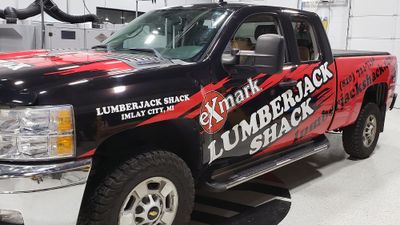 A commercial work truck with a custom vinyl wrap with red, white, and black logos and text with a grunge design