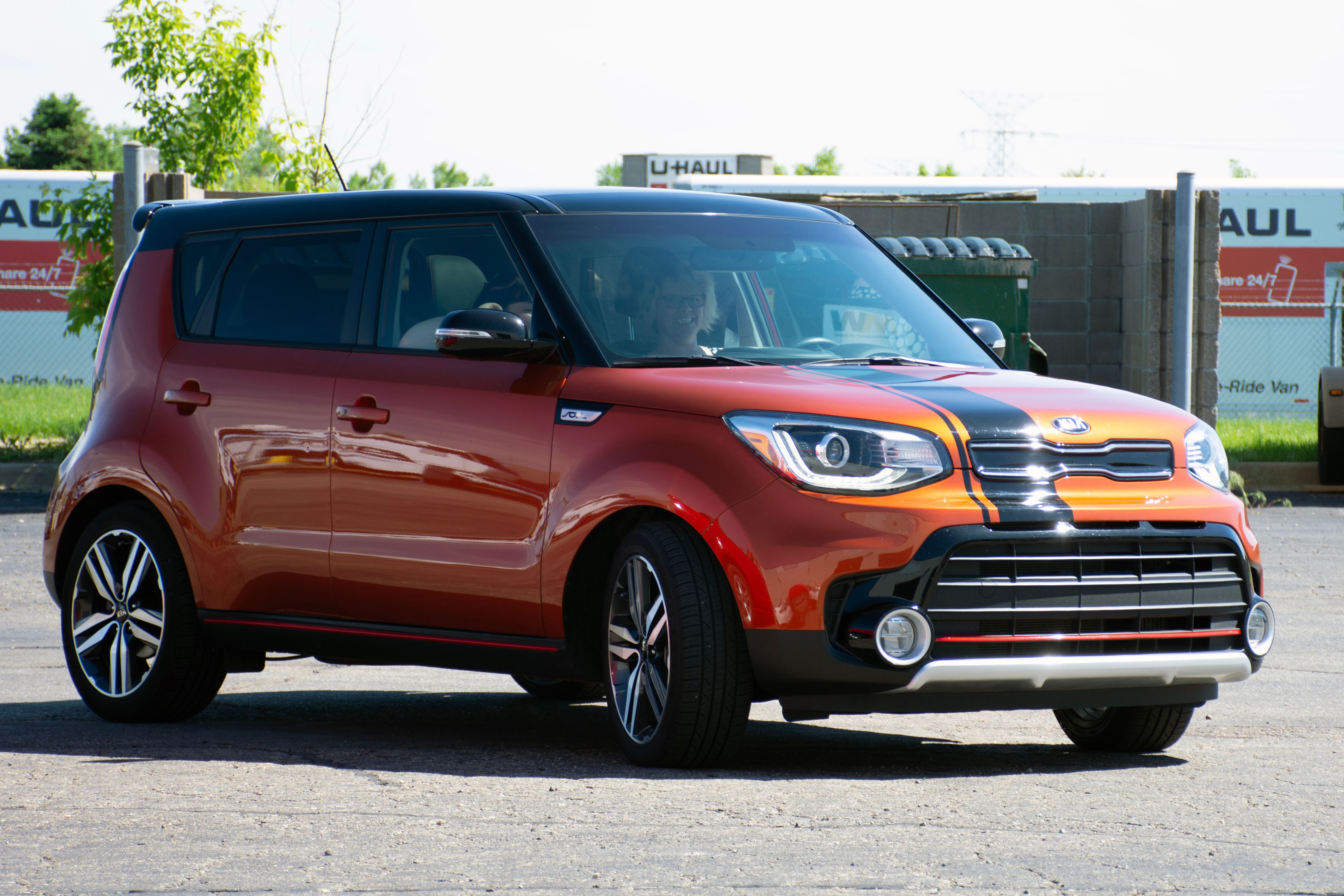 A personal kia car with a custom black accent stripe across the hood and roof