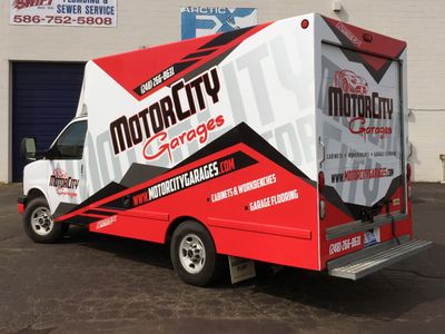 A commercial work box truck with a custom vinyl wrap with red, white, and black logos and text with a simple design