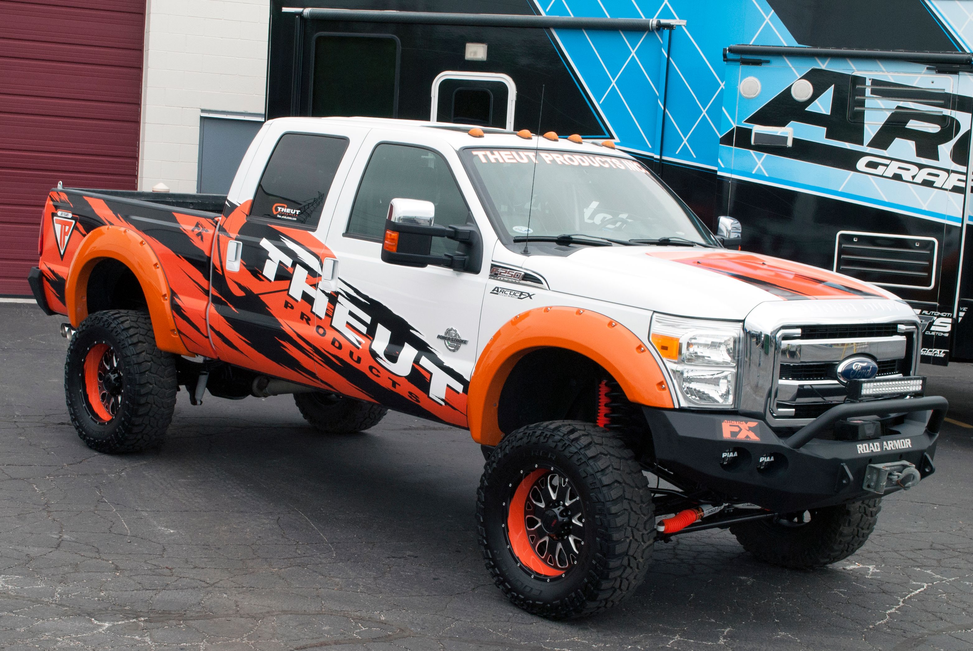 A commercial work truck with a custom vinyl wrap with orange, white, and black logos and text with a grunge design