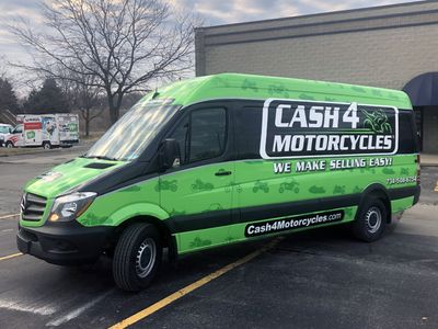 A commercial work van with a custom vinyl wrap with green, white, and black logos and text